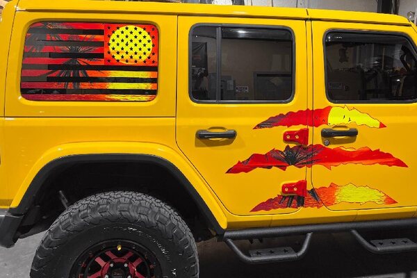 Custom sunset palm graphics on the rear window and doors of a yellow Jeep