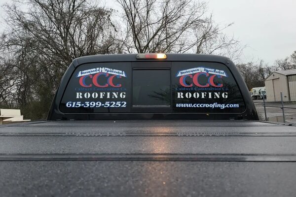Cut vinyl logo and phone number lettering on a truck rear window