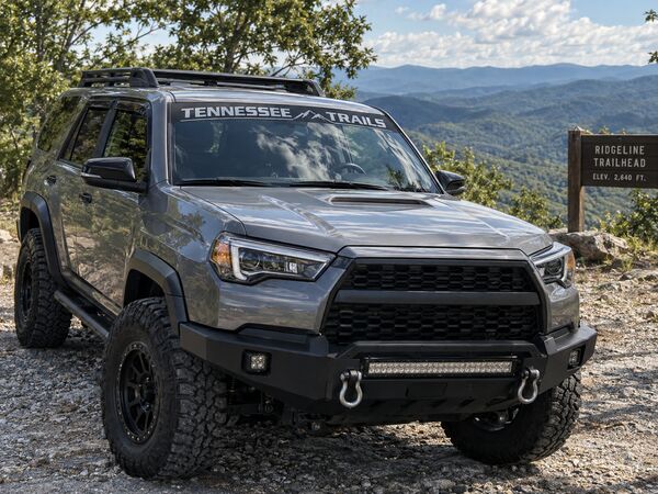 Gray off-road SUV with a custom Tennessee Trails windshield sunstrip banner at a mountain trailhead