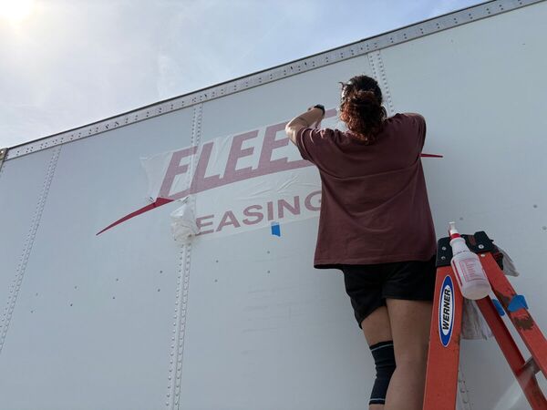 Installer applying fleet lettering to a box trailer