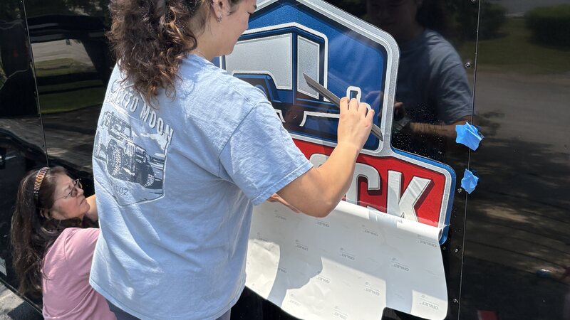 Smiles and Signs installer squeegeeing printed vinyl trailer graphics during a wrap installation