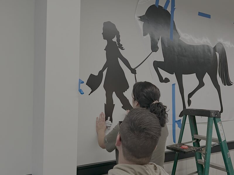 Installer applying a large die-cut wall mural to an interior wall
